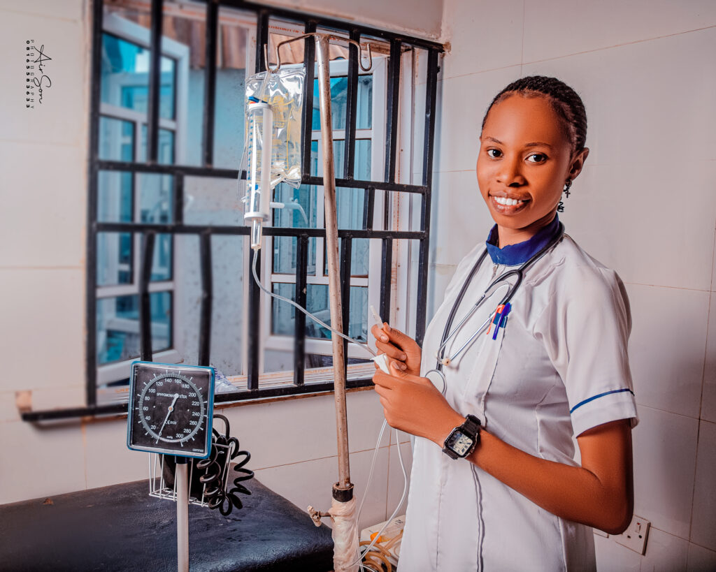 Nursing Student Practicing IV Setup – Victory College Clinical Lab - Victory College of Health Sciences and Technology Smiling female nursing student setting up an IV line in a clinical lab at Victory College, wearing a white uniform and stethoscope.
