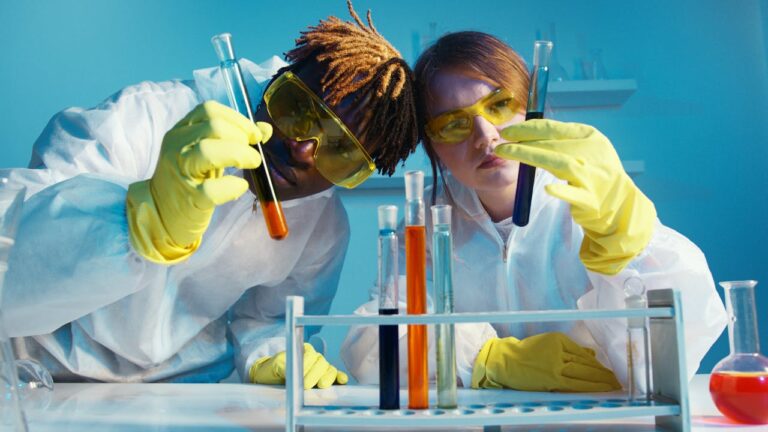 pexels-photo-5726837 - Victory College of Health Sciences and Technology Two scientists in protective gear analyzing test tubes in a laboratory setting.