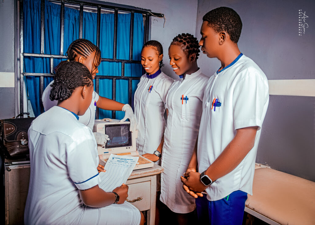 Student Nurses in Practical Training Session – Victory College of Health Sciences Group of student nurses in white uniforms practicing with medical equipment during a clinical training session at Victory College of Health Sciences.